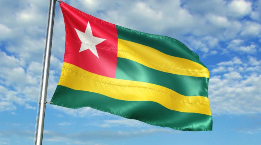 Togo flag on flagpole waving cloudy sky background realistic 3d illustration